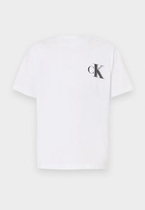 Balts kokvilnas T-krekls ar mazu melnu "cK" logotipu kreisajā krūtī. Klasiska apaļa apkakle, īsas piedurknes un brīvs piegriezums.