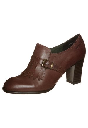 Brown leather heeled shoe with a rounded toe, decorative fringe detailing, and a buckle accent near the ankle. Textured wooden heel.