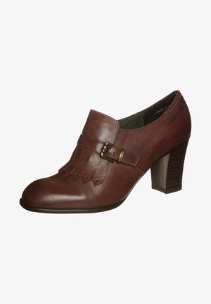 Chaussure à talon en cuir marron avec un bout arrondi, des détails de franges décoratives et une boucle près de la cheville. Talon en bois texturé.