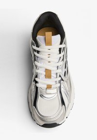 Białe i szare sportowe trampki z czarnymi i tanowymi akcentami, białymi sznurowadłami i górną częścią z siateczki, pokazane z widoku z góry.