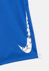 Kék sportnadrág fehér oldalsó panelekkel és egy torz fehér Nike ikonnal a szegély közelében.