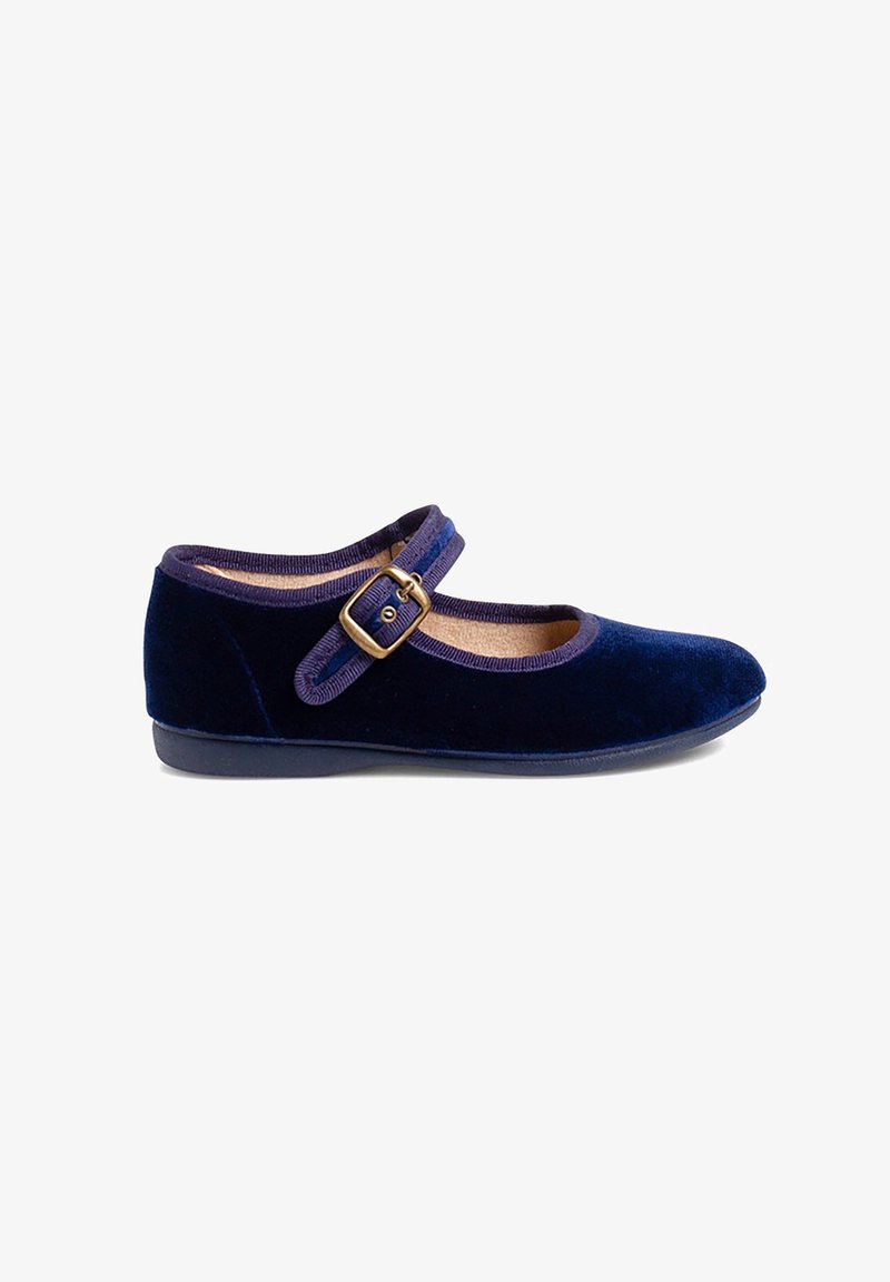 Une chaussure Mary Jane en velours bleu marine avec bride ajustable et boucle en laiton, semelle plate sur fond blanc.