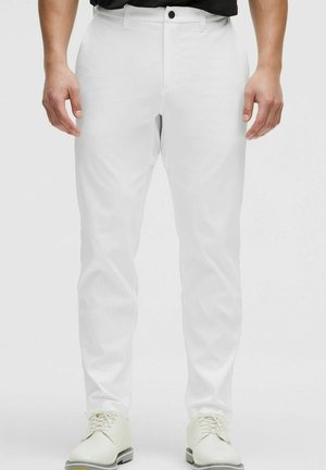 Weiße Hose mit geradem Bein, gefertigt aus einem glatten Stoff. Verfügt über einen Knopfverschluss, Gürtelschlaufen und Seitentaschen, kombiniert mit weißen Schuhen.