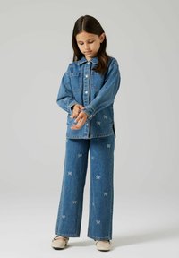 Teksariidest jakk ja püksid, sinise pesuga, valge kikilipsu tikandiga, mugava lõikega, nööpidega suletav jakk külje lõhikute jaotusega.