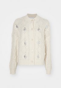 Kremfarget strikket cardigan med kabelmønster, prydet med sølvfargede paljetter og ribbestrikkede mansjetter og kant. Fem-knaps lukking foran.