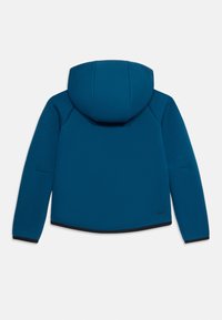 Jaqueta azul com capuz, mangas longas, acabamentos pretos nos punhos e na bainha, e pequeno logo preto da Nike perto da bainha inferior direita.
