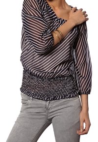 Blusa a righe blu navy e crema con maniche a tre quarti e vita arricciata. Materiale trasparente, texture leggera e vestibilità ampia.