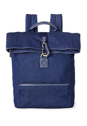 Mochila de mezclilla azul oscuro con asa superior, solapa plegable, cierre con gancho de metal y bolsillo frontal con cremallera, con detalles de costuras visibles.