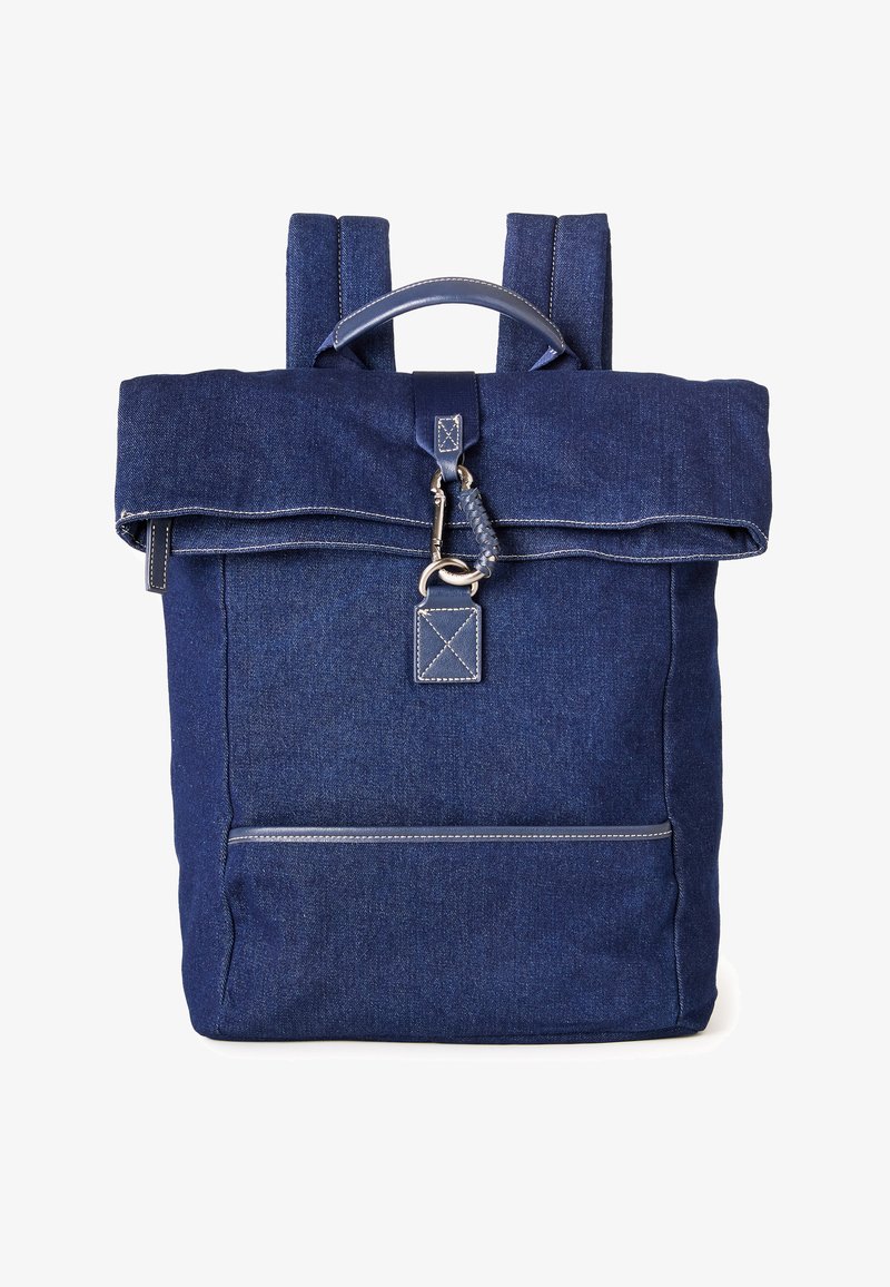 Zaino in denim blu scuro con maniglia superiore, patta pieghevole, chiusura con gancio metallico e tasca frontale con cerniera e dettagli di cuciture visibili.
