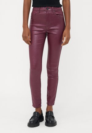 Bordo, sijo metalizirani skinny jeans z visokim pasom, dvema sprednjima žepoma in elegantnim krojem, kombinirani z črnimi loaferji.