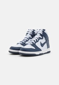 Navy and white high-top sneakers with perforated toe, lace-up front, padded collar, and textured rubber sole. Nike logo on side.