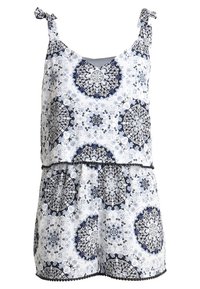 Bílé overály s námořnickými a černými mandala vzory. Má nastavitelné zavazovací ramínka a vrstvený design s třásněmi na lemovaní.
