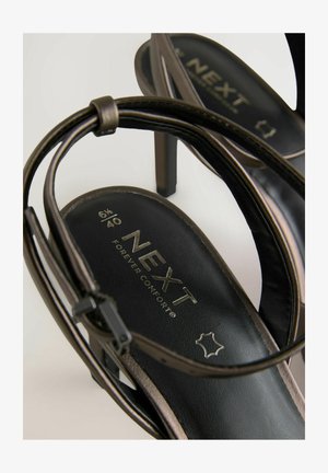 Svarta klacksandaler med en stilren remdesign. Innersulan har texten "NEXT FOREVER COMFORT" tillsammans med storlek 6½ och 40.