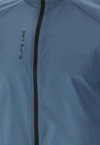Blå jakke med et glat, letvægtsstof, udstyret med en sort lynlås og "ELITE LAB"-logoet trykt på forsiden.