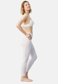 Leggings blancos fabricados con material elástico, con un diseño ajustado y corte hasta los tobillos. Combinados con un sujetador blanco.
