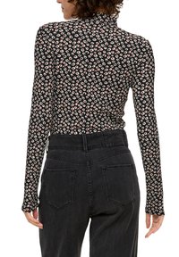 Długo rękawowa bluzka z czarnego materiału z małym różowym i kremowym wzorem zwierzęcym. Połączona z czarnymi dżinsami o wysokim stanie. Posiada stójkę.
