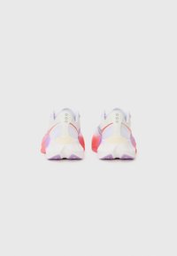 Zapatillas deportivas con parte superior de malla en blanco y acentos degradados en rojo, rosa y púrpura; suela gruesa con un diseño angular.