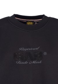 Czarny sweatshirt z okrągłym dekoltem, wykonany z bawełny. Posiada wytłoczone logo "GAS" oraz napis "Zarejestrowany znak towarowy" w szarym kolorze. Miękka faktura.