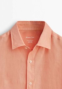 Chemise en lin couleur saumon avec boutons et col pointu, présentée à plat sur fond blanc.