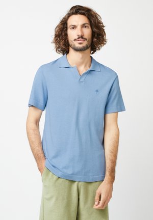 Lichtblauwe polo met korte mouwen, een klassieke kraag en een klein logo op de borst. Gemaakt van zacht materiaal met een licht gestructureerde afwerking.