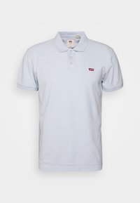 Světle modré polo tričko vyrobené z bavlny, s klasickým límečkem, tříknoflíkovou légou a malým červeným logem Levi's na hrudi.