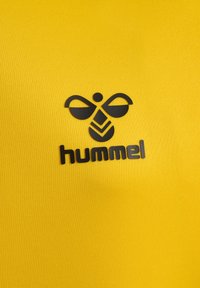 Zwart gestileerd bijenlogo met de tekst "hummel" op een felgele, gestructureerde stoffen achtergrond.