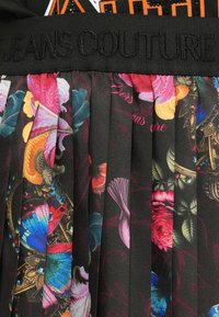 Gonna nera plissettata con motivi floreali e farfalle vivaci. Presenta una vita texturizzata con la scritta “JEANS COUTURE” in rilievo di colore nero.