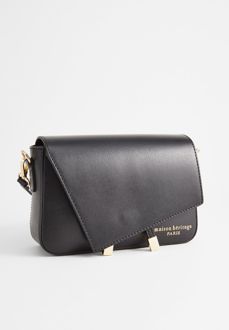 Czarna skórzana torba na ramię z trójkanciastą klapą, złotymi akcentami i wytłoczonym logo. Gładka tekstura i minimalistyczny design.