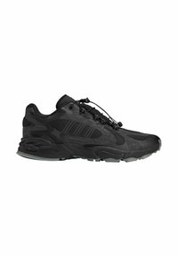 Black athletic shoe with a textured upper, integrated lacing system, and thick rubber sole. Features a dynamic design with subtle patterns.
