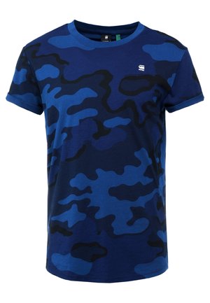 Sininen maastokuvioinen t-paita, joka on valmistettu puuvillasta. Paita on varustettu pyöreällä kaula-aukolla ja lyhyillä hihoilla. Suunnittelussa on käytetty erilaisia sinisen ja mustan sävyjä.