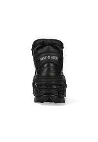 Schwarze High-Top-Sneaker aus strukturiertem Leder, mit dicker Sohle und Gummi-Akzenten. Verfügt über ein Logo auf der Rückseite und einen gepolsterten Schaft für zusätzlichen Komfort.