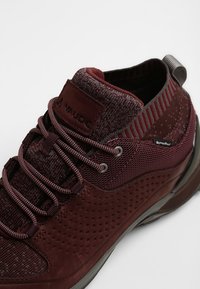 Bordeaux vandringsskor med en kombination av texturerad mesh och slätt mockaskinn, med förstärkta snörhål, detaljerad snörning och en flexibel sula.