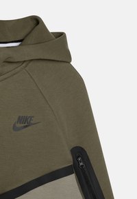 Felpa cappuccio verde oliva con logo Nike nero, dotata di tasca con zip e pannello nero a contrasto all'orlo, realizzata in tessuto morbido.