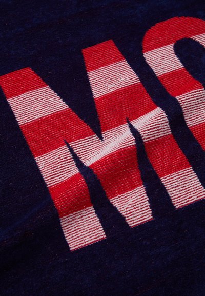 Tissu bleu marine avec un motif rayé rouge et blanc formant les lettres "M" et "O", présentant une surface texturée.