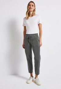Grijze joggerbroek met elastische taille en zijzakken, gecombineerd met een eenvoudig wit t-shirt met korte mouwen en witte sneakers.