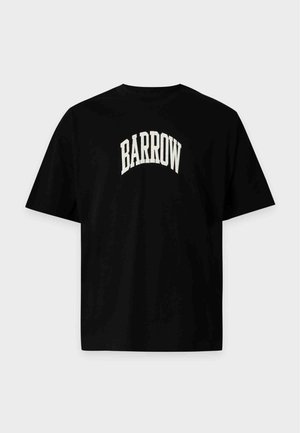 Άνδρας που φοράει μαύρο T-shirt Barrow και μαύρο παντελόνι με κόκκινες ρίγες, στέκεται με τα χέρια στις τσέπες μπροστά σε απλό φόντο.
