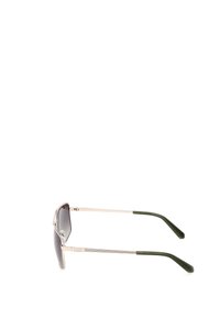 Gafas de sol con un marco de metal plateado, lentes de gradiente gris oscuro y patillas de plástico verde. Presentan una textura sutil en el marco.