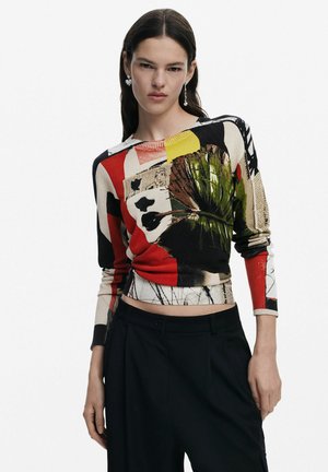 Top lavorato a maglia multicolore con motivi grafici, tra cui volti e foglie, con maniche lunghe e scollatura rotonda. Abbinato a pantaloni neri.