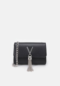 Sac à main en cuir noir texturé avec fermoir à rabat, bandoulière en chaîne argentée et un gland métallique décoratif avec un accent en "V".