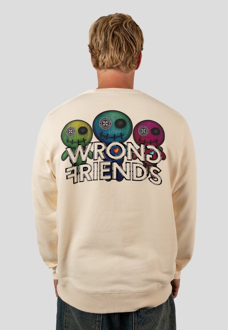 Felpa girocollo color crema con una grafica di tre teschi colorati con bottoni al posto degli occhi, e il testo "WRONG FRIENDS" sottostante.
