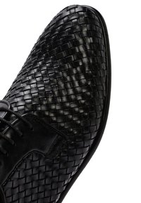 Chaussure en cuir tressé noir avec un bout lisse et un corps texturé. Présente un design à lacets et une silhouette élégante. Semelle extérieure en caoutchouc durable.