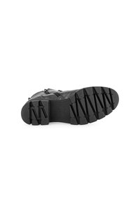 Bottine en cuir noir avec une tige texturée, présentant une semelle en caoutchouc contrastante avec de profondes rainures pour l'adhérence et une fermeture éclair sur le côté.