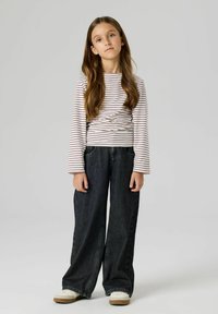 Długi rękaw, bluzka w paski w kolorze białym i bordowym, zestawiona z szerokimi ciemnymi dżinsami oraz lekkimi sneakersami z teksturowaną podeszwą.