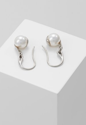 Hopeiset koukkukorvakorut, joissa kummassakin on suuri valkoinen helmi valkoisella lohkopedestalilla.