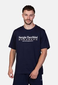 T-shirt blu navy in cotone, con colletto a giro e maniche corte, decorato con un logo stampato bianco e bandiere sul davanti.