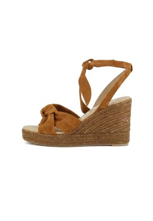 Sandalo con zeppa in camoscio marrone con cinturino frontale annodato, legatura alla caviglia e suola platform in corda intrecciata.
