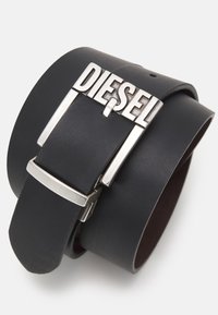 Ceinture en cuir noir avec une large sangle et une boucle en métal argenté embossée du mot "DIESEL". Texture lisse avec un léger éclat.