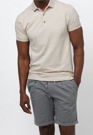 Polo shirt beige à manches courtes avec deux boutons, associé à un short gris avec une taille élastique et un ourlet roulé. Tissu à texture lisse.