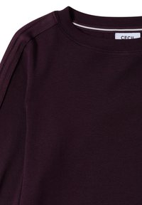 Burgundowa bluza z okrągłym dekoltem, teksturowanymi akcentami na ramionach i gładkim wykończeniem. Materiał jest miękki i elastyczny, co zapewnia wygodne dopasowanie.