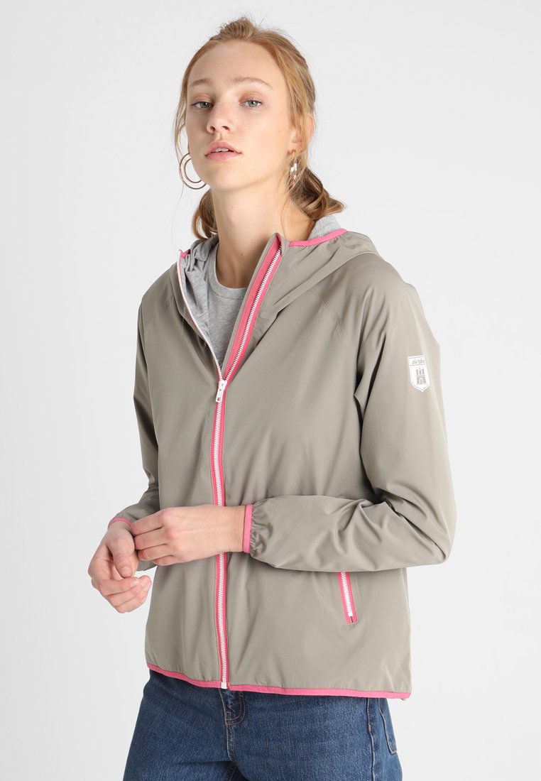 Lichtgrijze windbreakerjas met roze accenten, een capuchon en een rits. Voorzien van elastische manchetten en een casual pasvorm, gedragen over een grijze shirt.
